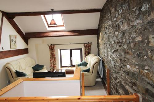a living room with a stone wall and couches at The Hayloft, Broughton Beck, near Ulverston in Spark Bridge