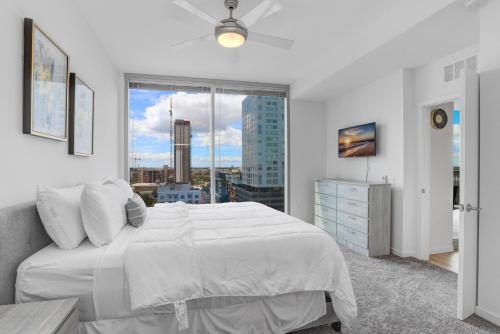 a white bedroom with a large bed and a window at Stunning 2-Bed Condo with Panoramic DT Tampa Views in Tampa