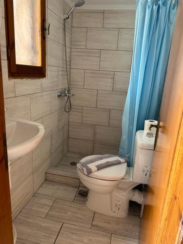 a bathroom with a toilet and a sink and a shower at Joanna Rooms in Skala Eresou