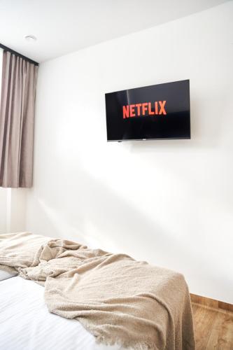 a bed in a bedroom with a netflix sign on the wall at Na Fursie Apartments & Rooms in Nowy Targ