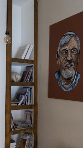 a painting of a man on a wall next to a book shelf at Hotel Urbano Ventia in Comodoro Rivadavia