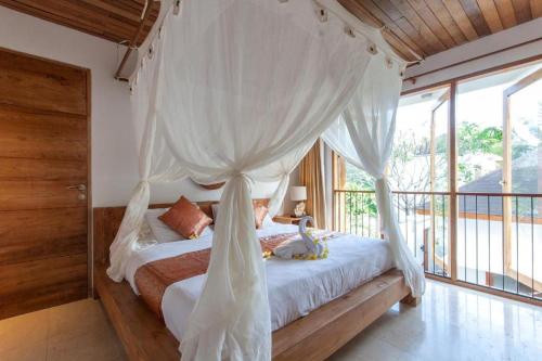 ein Schlafzimmer mit einem Himmelbett mit weißen Vorhängen in der Unterkunft 3 Bedroom Private Villa Ubud in Ubud