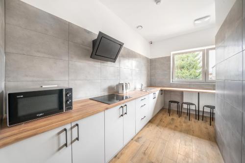 a kitchen with white cabinets and a sink and a microwave at Na Fursie Apartments & Rooms in Nowy Targ