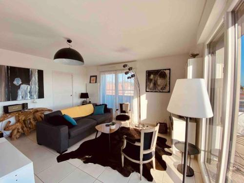 uma sala de estar com um sofá e uma mesa em Magnifique appartement avec sa grande terrasse em Touques