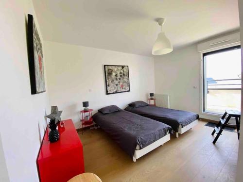 um quarto com 2 camas e uma mesa vermelha em Magnifique appartement avec sa grande terrasse em Touques