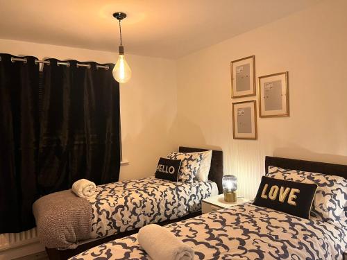 sypialnia z dwoma łóżkami i oknem miłości w obiekcie Modern Renovated 2-Bedroom House w mieście Barking