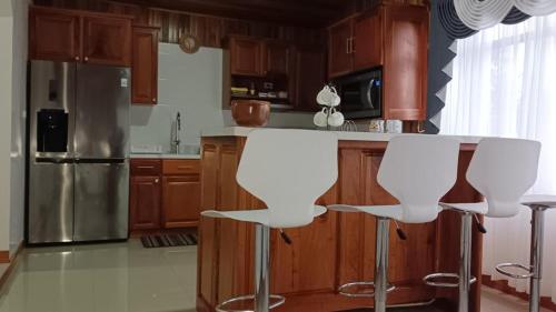 a kitchen with wooden cabinets and white bar stools at Monteverde Guesthouse in Monteverde Costa Rica