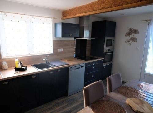 - une cuisine avec des placards noirs, un évier et une table dans l'établissement Maison au cœur du Minervois, à Pouzols-Minervois