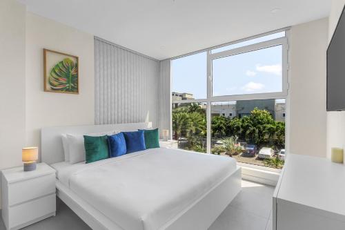 Bocobay Aracari Condo Hotel في شاطئ بالم إيغل: غرفة نوم بيضاء مع سرير ونافذة كبيرة