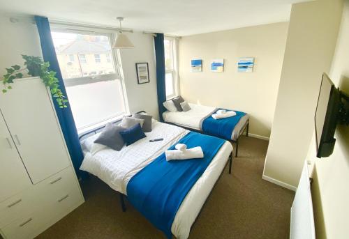 twee bedden in een kamer met blauw en wit bij Group stays Wolverhampton M6 J10 in Bilston