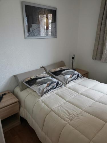 a white bed with two pillows on it in a room at Appartement "ENTOURLOUP" classé 2 étoiles in Le Dévoluy