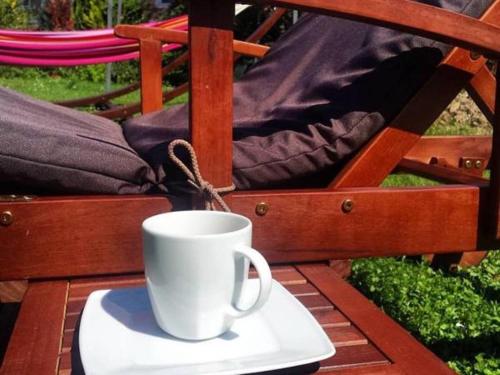 a white coffee cup sitting on a plate on a table at SkiBike House Stronie Śląskie in Stronie Śląskie