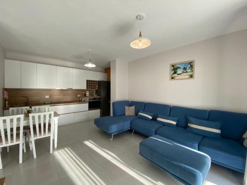 ein Wohnzimmer mit einem blauen Sofa und einer Küche in der Unterkunft Avenir Apartment in Durrës