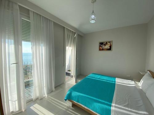 ein Schlafzimmer mit einem Bett und einem großen Fenster in der Unterkunft Avenir Apartment in Durrës