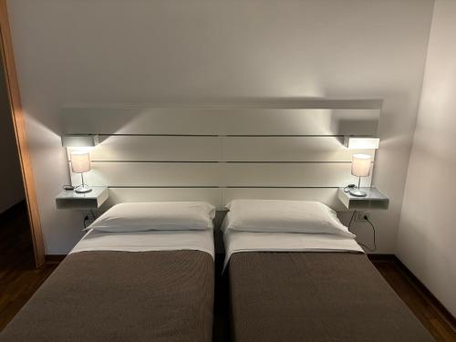 two beds in a room with two lamps on the wall at ESSENTIAL ROOM & PARKING in Centro Città con Parcheggio Privato e WIFI in Potenza