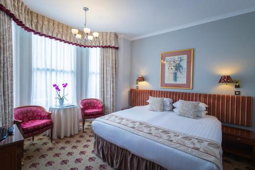 um quarto de hotel com uma cama, uma mesa e cadeiras em London Lodge Hotel em Londres