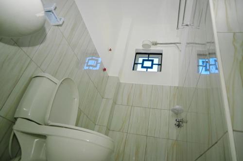 a bathroom with a toilet and a shower with stickers on the wall at Shali Hotel in Wote
