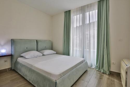 a bedroom with a bed and a large window at Royal Gardens Paradise in Budva