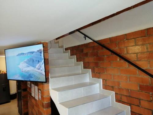 Una escalera con una pared de ladrillo y una TV. en Orquidia 12 en Salento