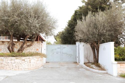 une allée avec un portail bleu et deux arbres dans l'établissement Luoghi di Puglia, à Ostuni