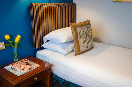 a hotel room with a bed and a table with a magazine at London Lodge Hotel in London