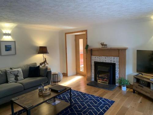 a living room with a couch and a fireplace at Ivy Cottage, Aberfeldy - Highland Perthshire in Aberfeldy