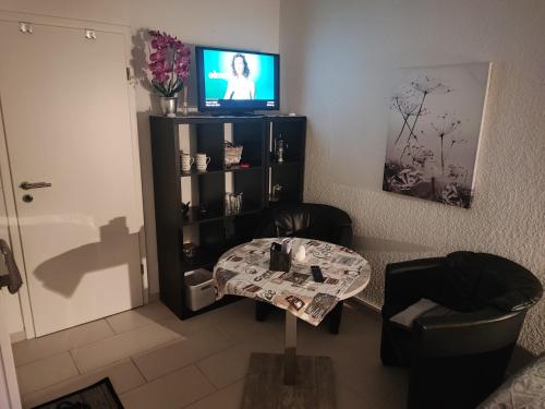 sala de estar con mesa y TV en Appartment zur Ruhe Forsterweg 6, en Hameln