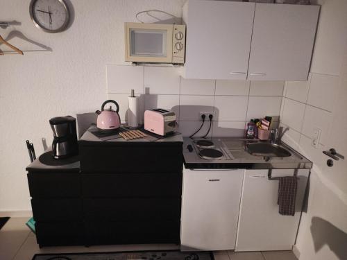 una pequeña cocina con fregadero y microondas en Appartment zur Ruhe Forsterweg 6, en Hameln