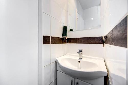 uma casa de banho branca com um lavatório e um espelho em London serviced apartments BAFOG em Barking