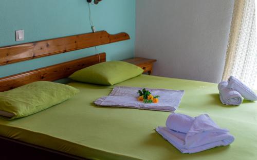 Una cama verde con toallas y flores. en Giola Apartments And studios 1, en Astris