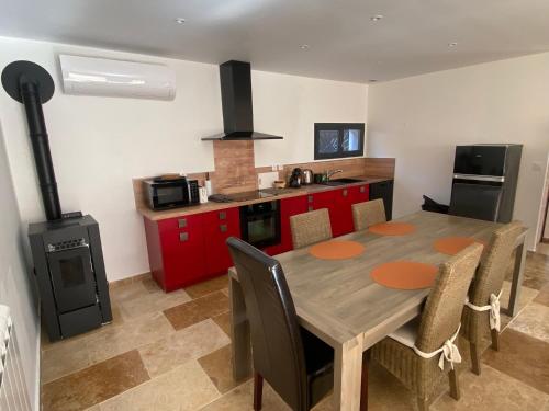 une cuisine avec une table en bois et des placards rouges dans l'établissement Agréable dépendance 3 pièces, à Saint-Maximin-la-Sainte-Baume