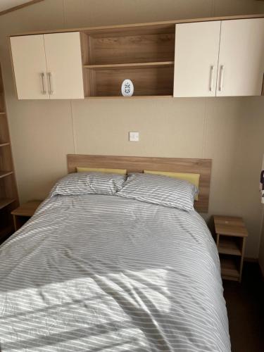 um quarto com uma cama com um relógio na parede em 8 Berth family caravan Selsey West Sussex em Selsey
