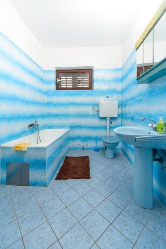 a blue tiled bathroom with a tub and a toilet at Apartmani Katica in Kornić