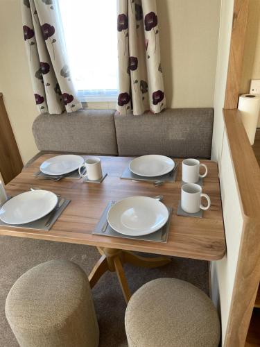a wooden table with plates and mugs on it at 8 Berth family caravan Selsey West Sussex in Selsey