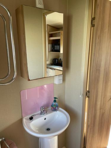uma casa de banho com um lavatório branco e um espelho. em 8 Berth family caravan Selsey West Sussex em Selsey