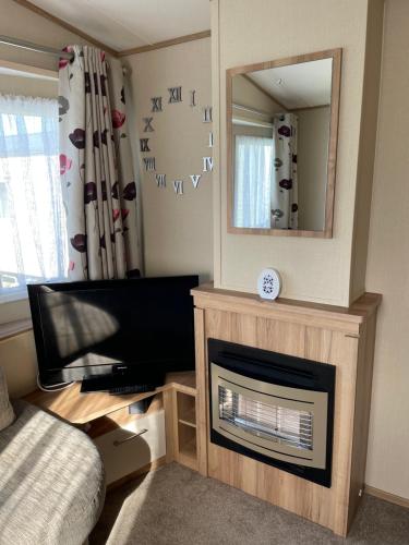 a living room with a fireplace and a mirror at 8 Berth family caravan Selsey West Sussex in Selsey