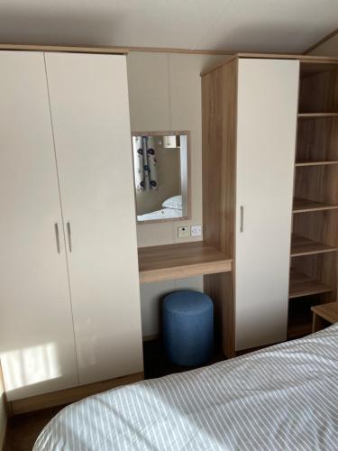 a bedroom with a bed and cabinets and a mirror at 8 Berth family caravan Selsey West Sussex in Selsey