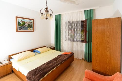 a bedroom with a bed and a chair in it at Apartmani Katica in Kornić