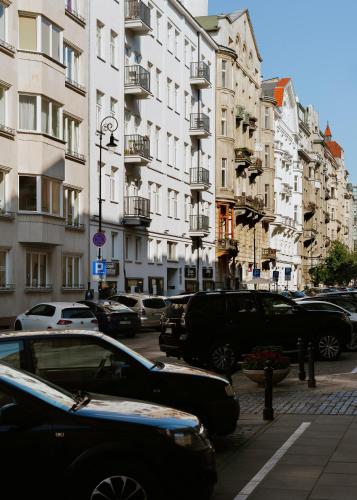 a city street with cars parked in front of tall buildings at Lwowska Studios - STAYINWARSAW in Warsaw