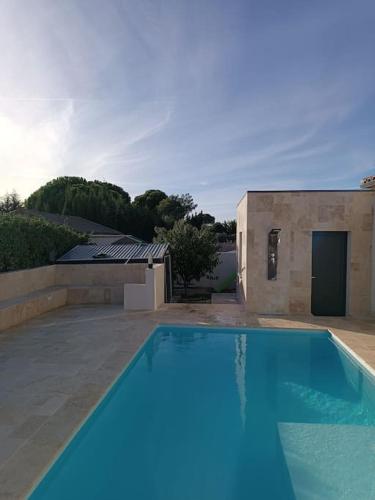 une piscine bleue en face d'un bâtiment dans l'établissement Charmant studio avec piscine, à Villemoustaussou