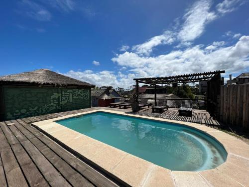 a swimming pool on a wooden deck next to a wooden deck at Pueblo Arriba Hostel in Punta Del Diablo