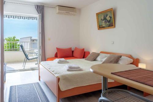 a bedroom with a bed and a table and a balcony at Baska Voda Apartment 7 in Baška Voda