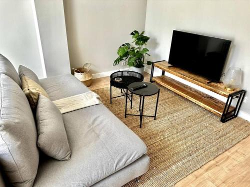 een woonkamer met een bank en een flatscreen-tv bij Aurora 2 bedroom Apartment in Rotterdam