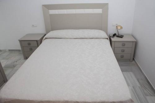 um quarto com uma cama grande e duas mesas de cabeceira em Apartamento junto al mar en Torrox Costa em Málaga