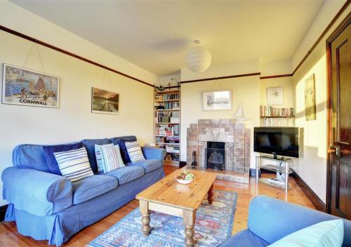 a living room with a blue couch and a fireplace at Trearth in St Merryn