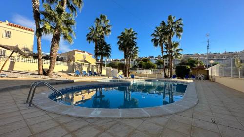 a swimming pool with palm trees in a courtyard at Casa Blue Lagoon KLIMA FREE WIFI POOL SAT TV in San Miguel de Salinas