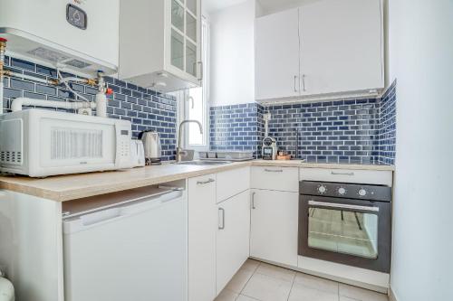 a kitchen with white cabinets and a microwave at Magnifique studio rénové gare 2per wifi in Joinville-le-Pont