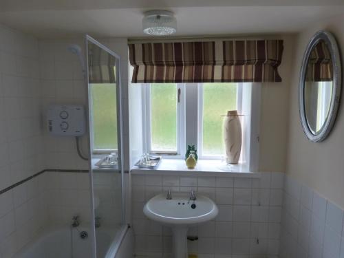 uma casa de banho com um lavatório e uma janela em Wood End Cottage em Slaithwaite