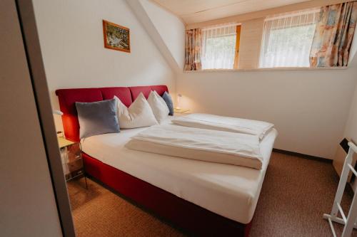 Dormitorio pequeño con cama con cabecero rojo en Ferienhäuser Inge und Seeblick, en Oberaichwald