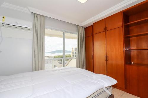 1 dormitorio con cama y ventana grande en Maravilhoso apartamento vista para o mar - AI01I, en Florianópolis